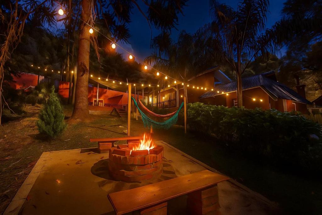 una hoguera en un patio trasero por la noche con luces en Pousada Villa Bergamin, Monte Verde, en Monte Verde