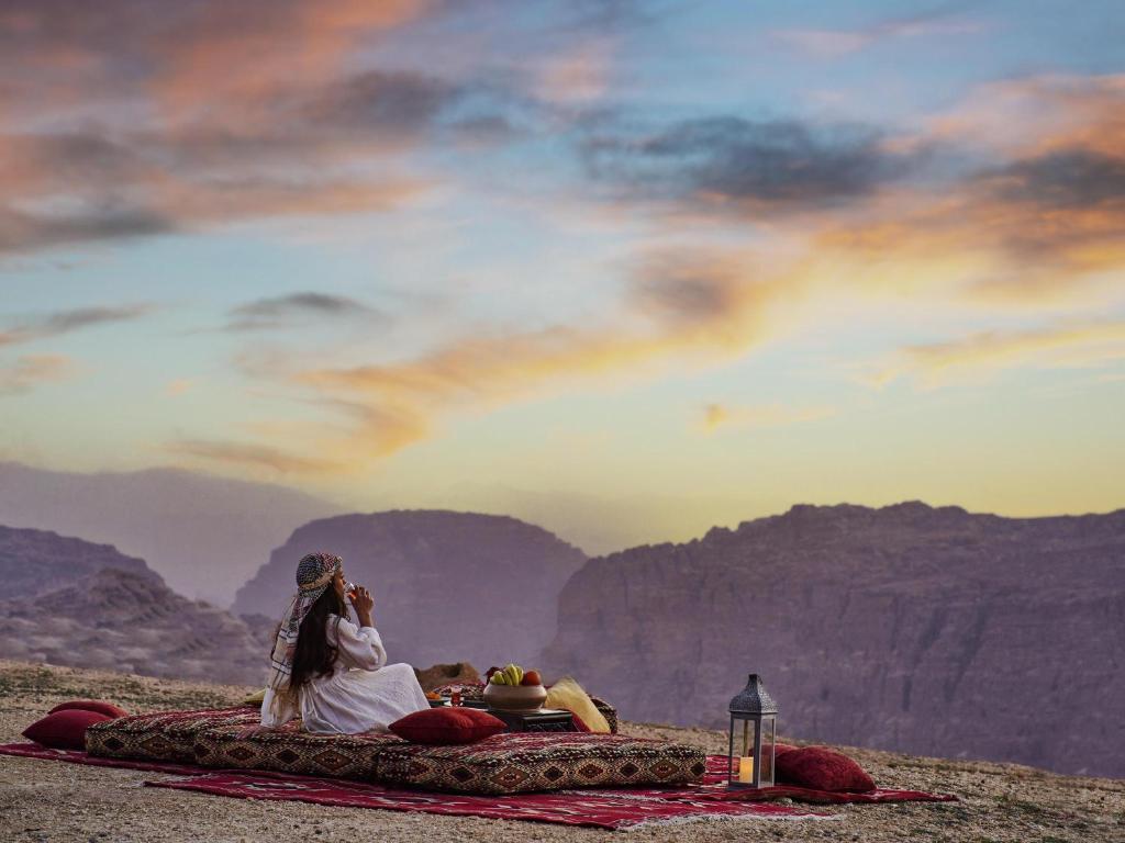 a couple of people laying on a blanket in the mountains at Grand Mercure Petra in Wadi Musa