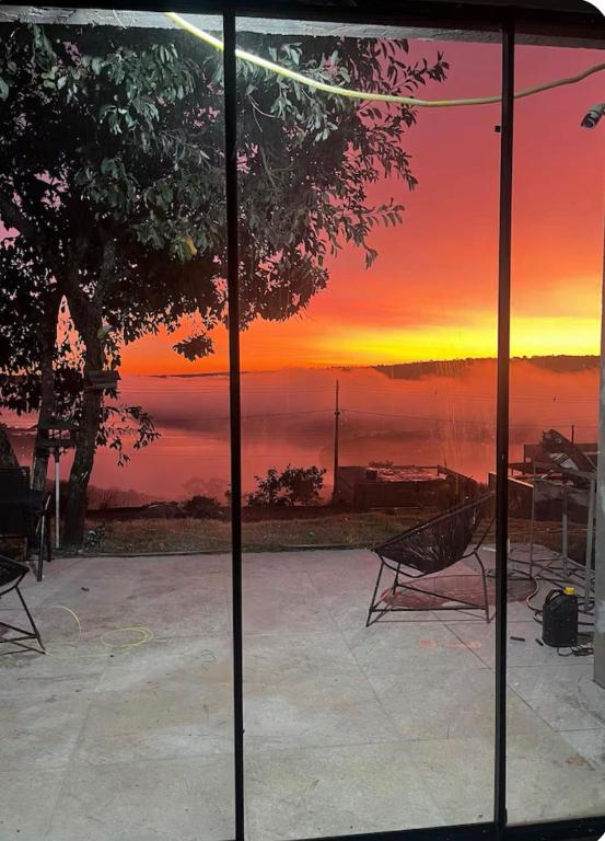 a view of a sunset through a glass window at Casa no Lago em Corumbá 4 in Alexânia