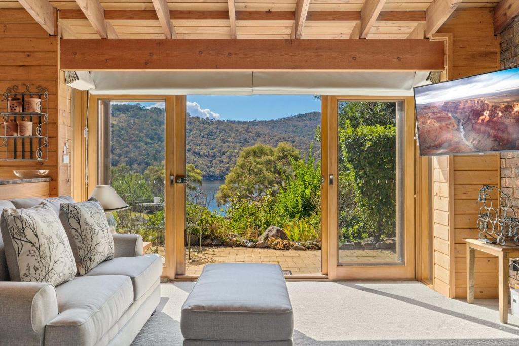 a living room with a couch and a large window at The Wolery - Lakeside Jindabyne in Jindabyne