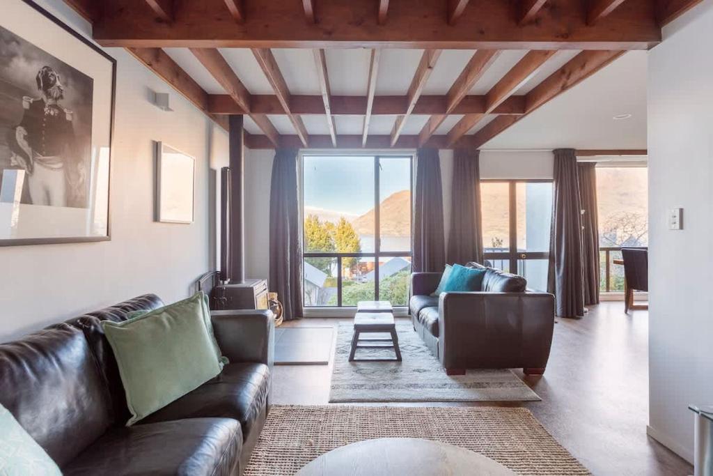 een woonkamer met lederen meubels en een groot raam bij The Twins in Queenstown