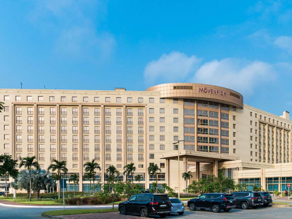 Un gran edificio con coches aparcados delante. en Mövenpick Ambassador Hotel Accra, en Accra