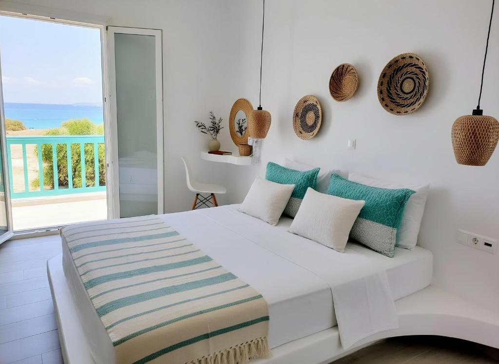 a white bedroom with a large white bed with pillows at Beachfront Private Suites at Kalais - Stunning Sea & Sunset Views, Bus Stop Outside, Easy Naxos Town Access, Free Beach Chairs in Plaka