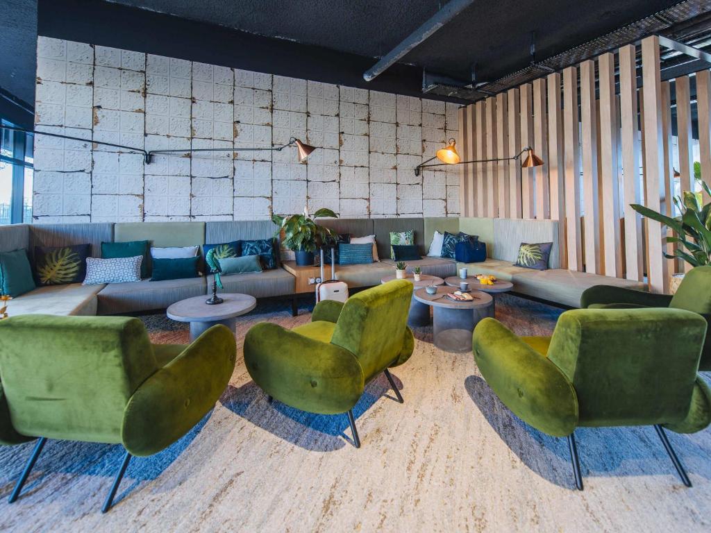 a living room with green chairs and a couch at Ibis Styles Rouen Centre Rive Gauche in Rouen