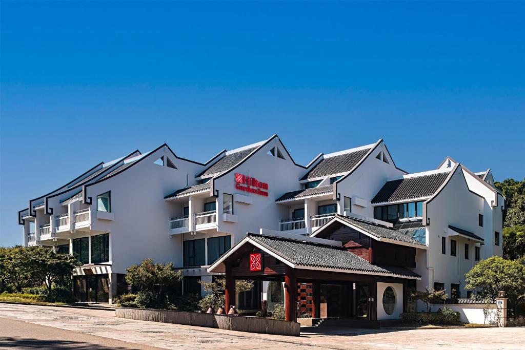 un grande edificio bianco con un ristorante di fronte di Hilton Garden Inn Zhoushan Mount Putuo a Zhoushan