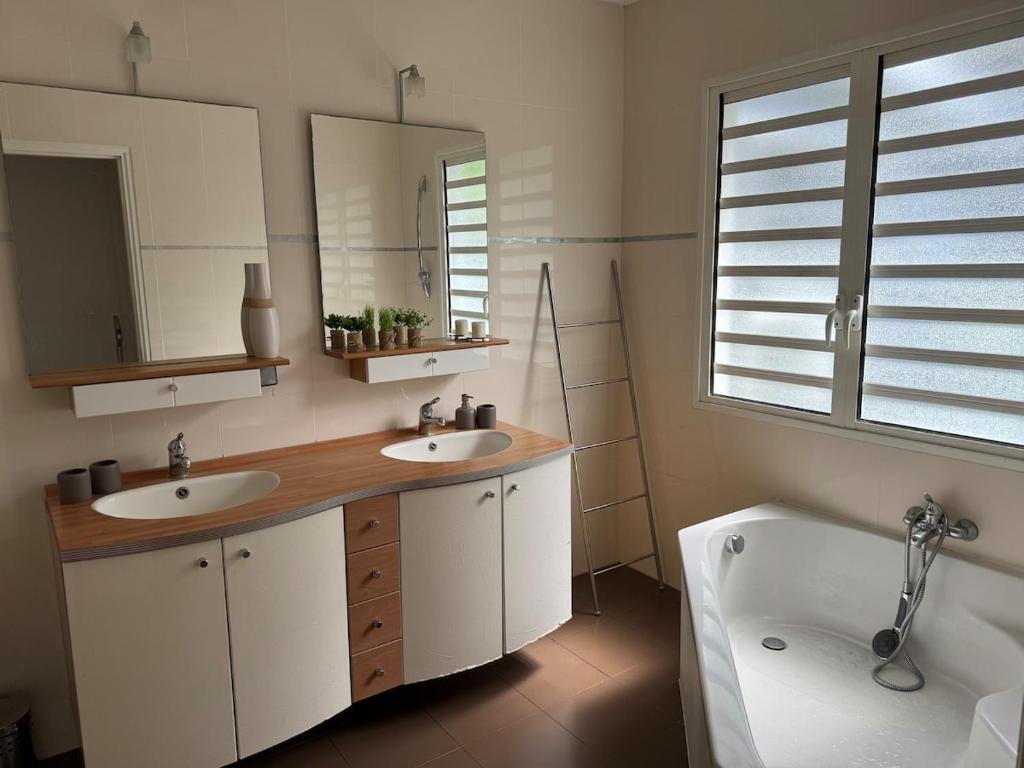 a bathroom with two sinks and a tub and a mirror at villa Whakata in Saint-Leu