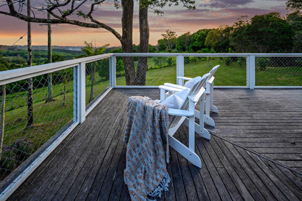 two white chairs sitting on a wooden deck at Hinterland Retreat l Fire Pit Scenic Views l Nova Escapes in Goonengerry