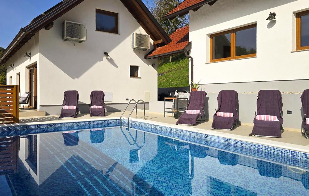 a swimming pool with purple lounge chairs next to a house at Holiday Home With Pool in Tuheljske Toplice