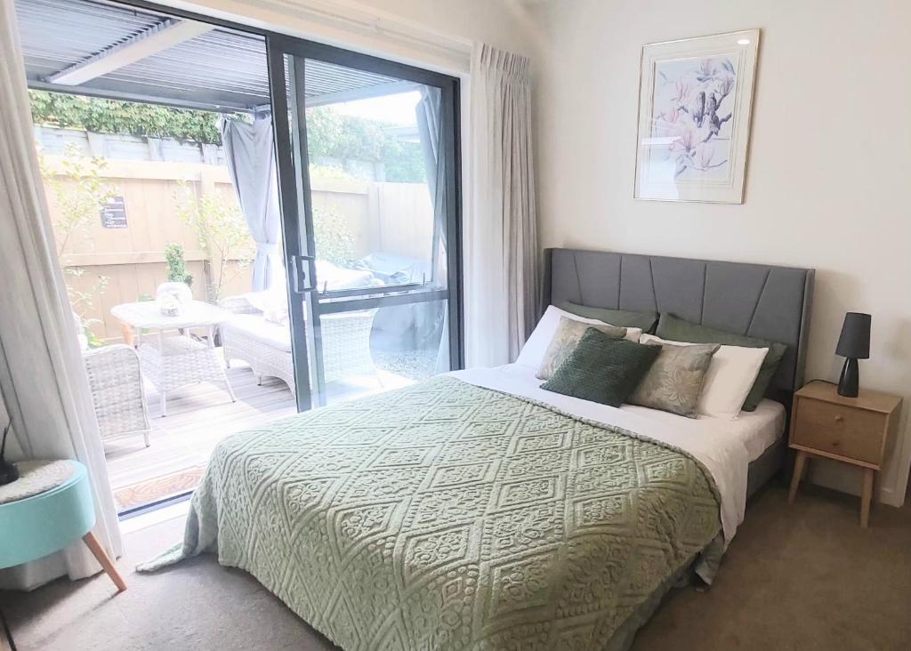 Un dormitorio con una cama y una puerta corrediza de vidrio. en Nature Escape Near Orewa Beach, en Silverdale