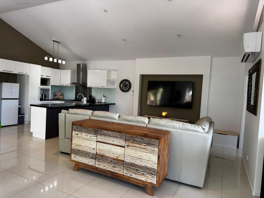a living room with a couch and a kitchen at Rest & Relax at The Secret Garden Getaway in Harrisons Pocket