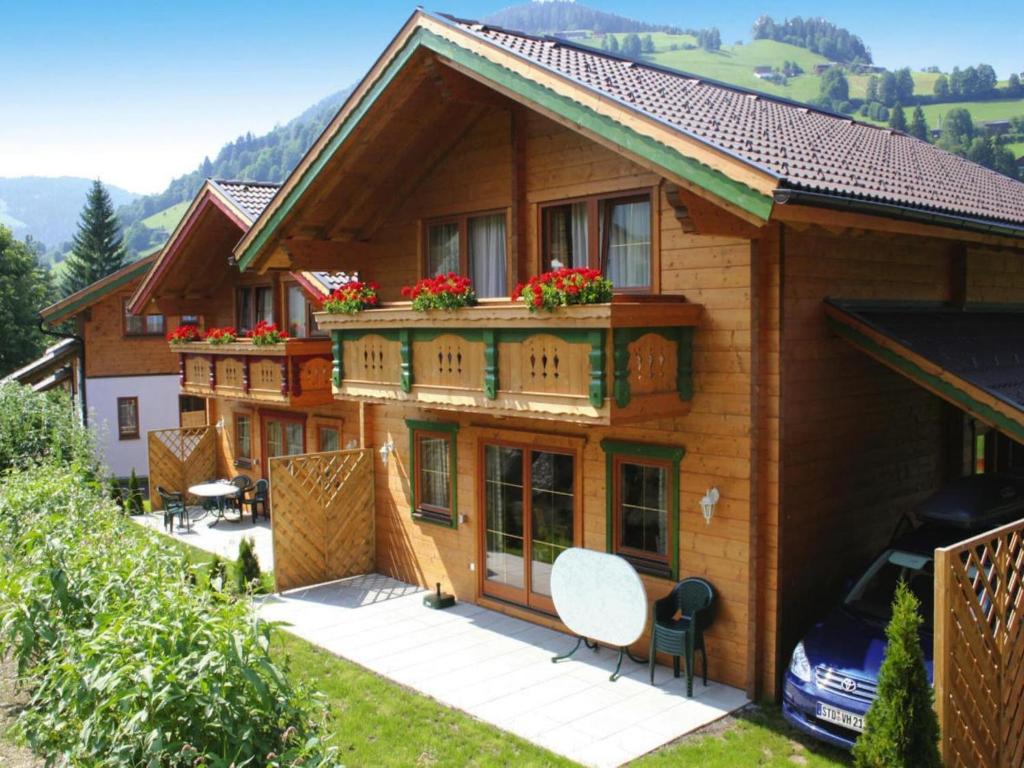 a house with a balcony with flowers on it at Feriendorf Wildschönau Alpine comfort with family in Niederau