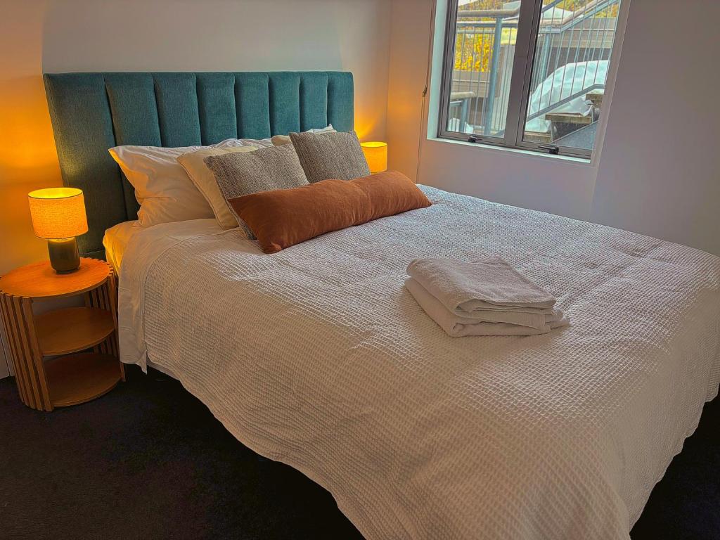 a bedroom with a large white bed with a blue headboard at Comfortable in Central Wanaka and Free Parking in Wanaka