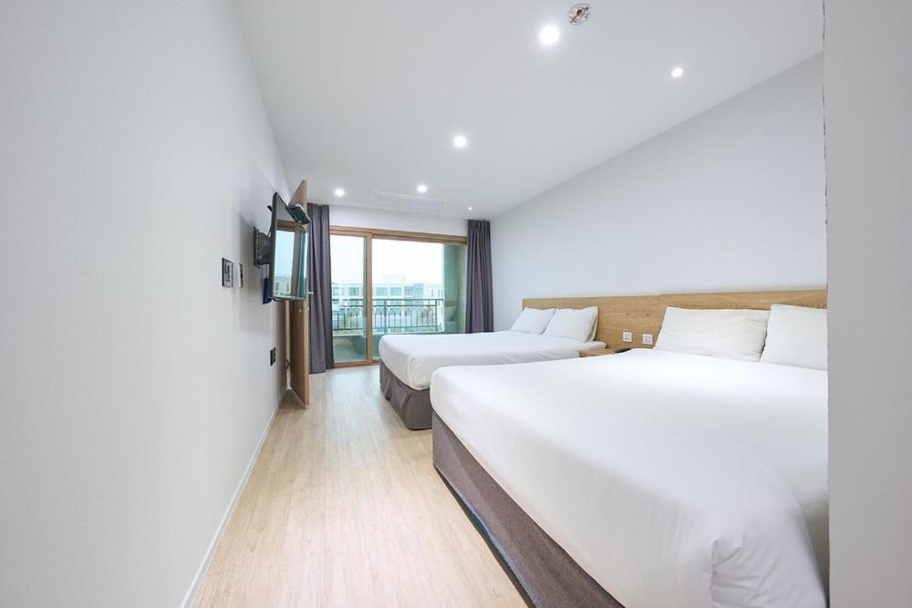 Una habitación de hotel con dos camas y una ventana. en Seogwipo Pension Yeonri, en Yerye-dong