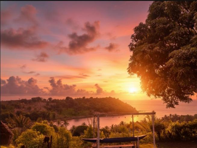 un coucher de soleil sur une masse d'eau avec un banc dans l'établissement Lambawany, sur l'île Sainte-Marie