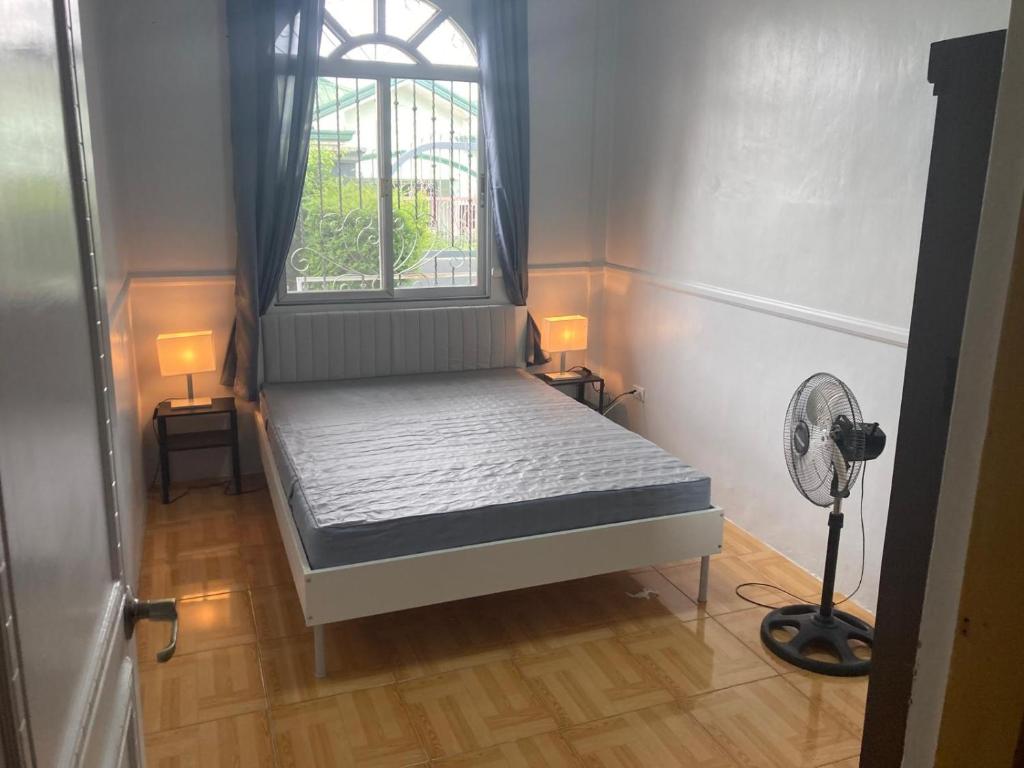 a bed in a room with a window and a fan at fully appartement in Quitangil