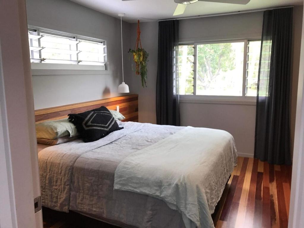 a bedroom with a large bed and a window at Coastal 4 bedroom Sawtell home with Pool in Sawtell
