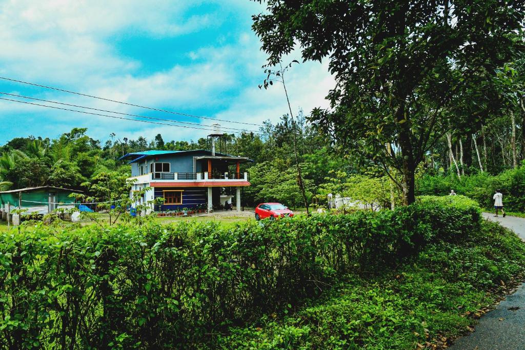 a house with a car parked in front of a hedge at Rainy Cloud Homestay 3B, Balcony, Home Food in Chikmagalūr
