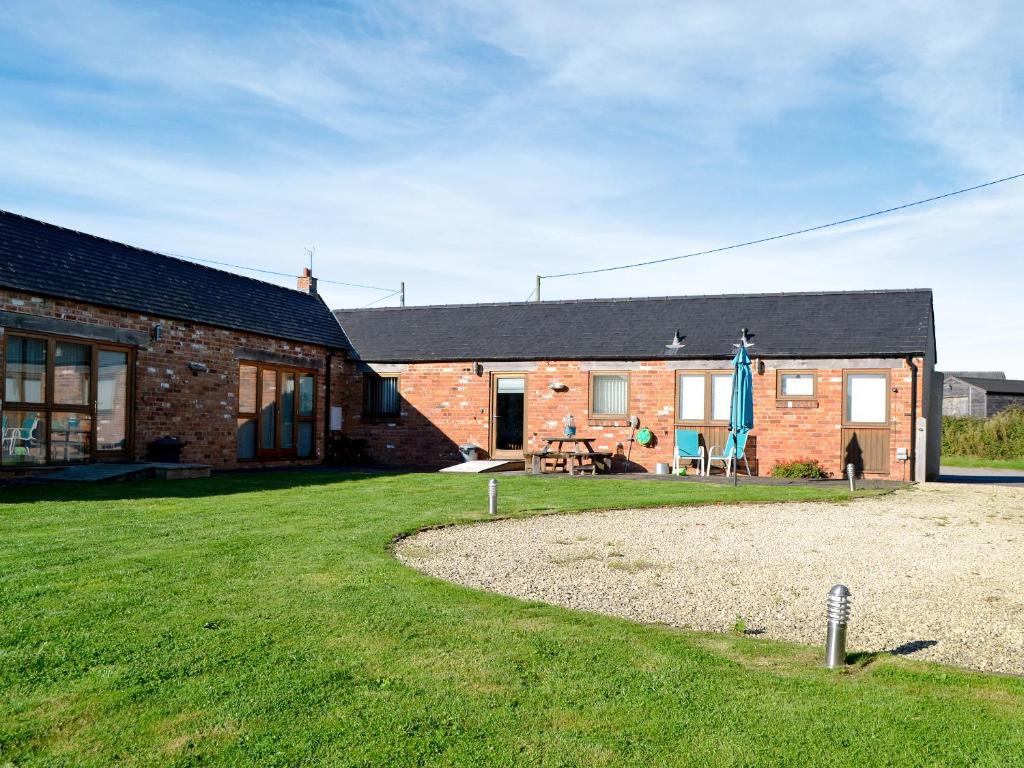 a brick house with a grass yard in front of it at Bramble Barn in Tortworth