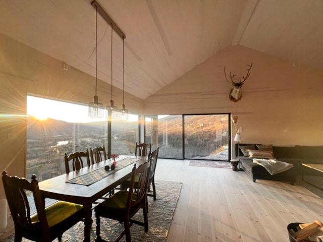 ein Esszimmer mit einem Tisch, Stühlen und einem Klavier in der Unterkunft New Cabin With Panoramic Views At Hardangervidda in Maurset