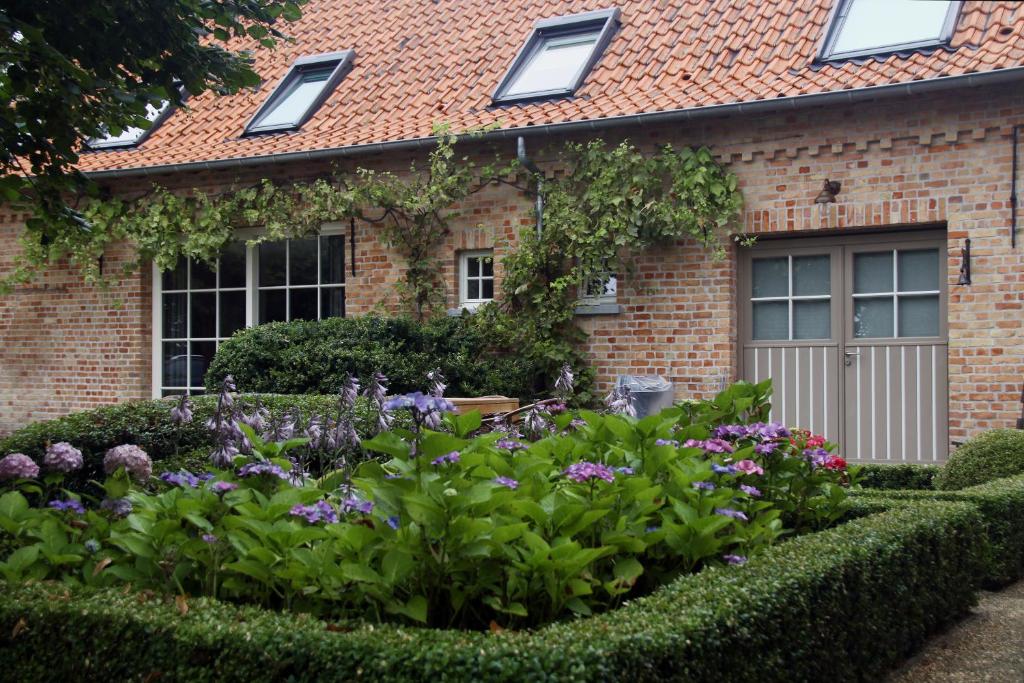 um jardim em frente a uma casa de tijolos com flores em Wilgenwind em Sijsele