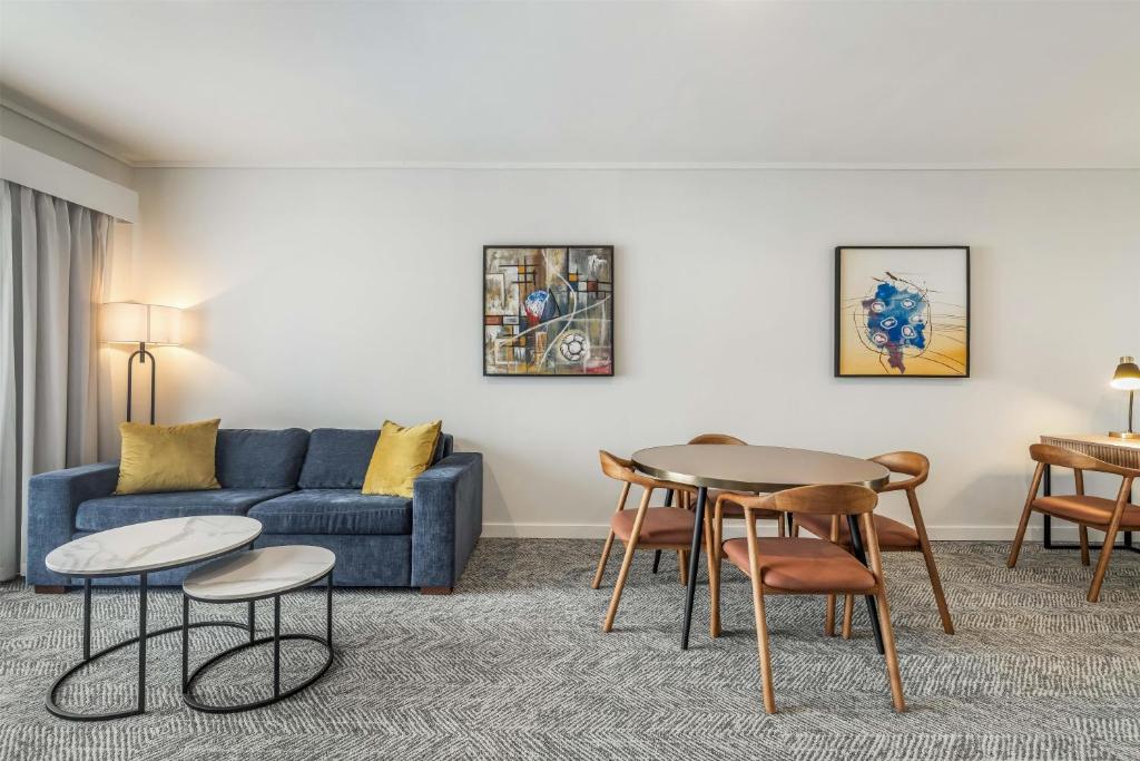 Una sala de estar con un sofá, una mesa y sillas. en Adina Apartment Hotel Perth Barrack Plaza, en Perth