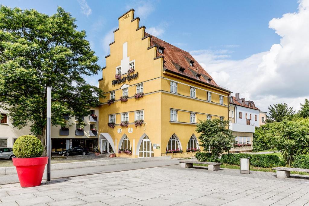 Um edifício amarelo com um balde vermelho à frente. em Altstadt-Hotel em Amberg