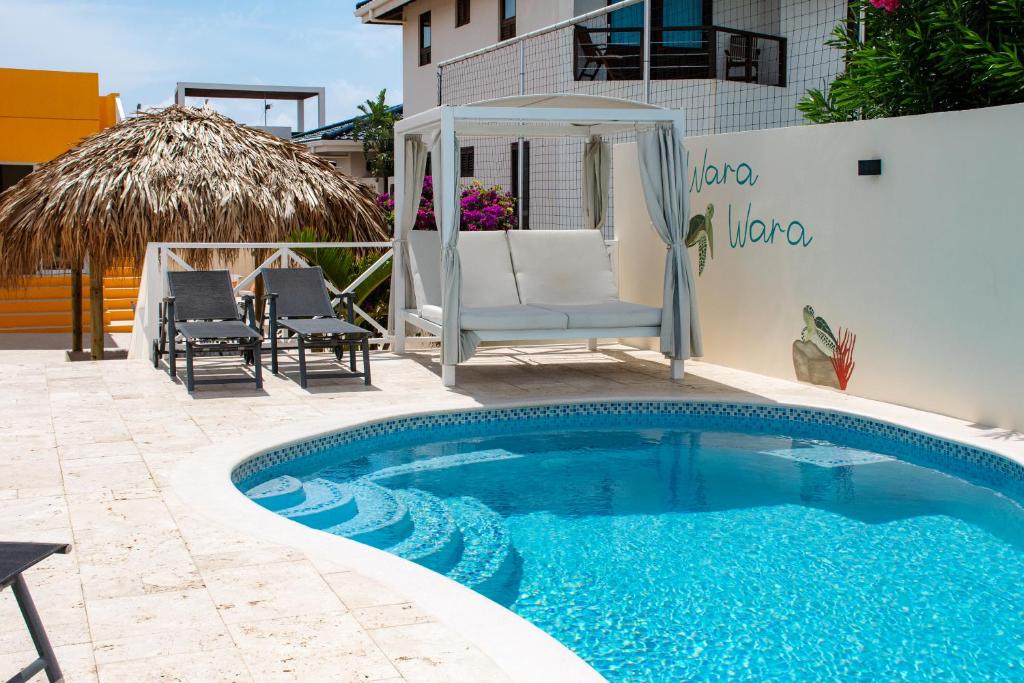a swimming pool with chairs and a gazebo at WaraWara Mini resort in Jan Thiel