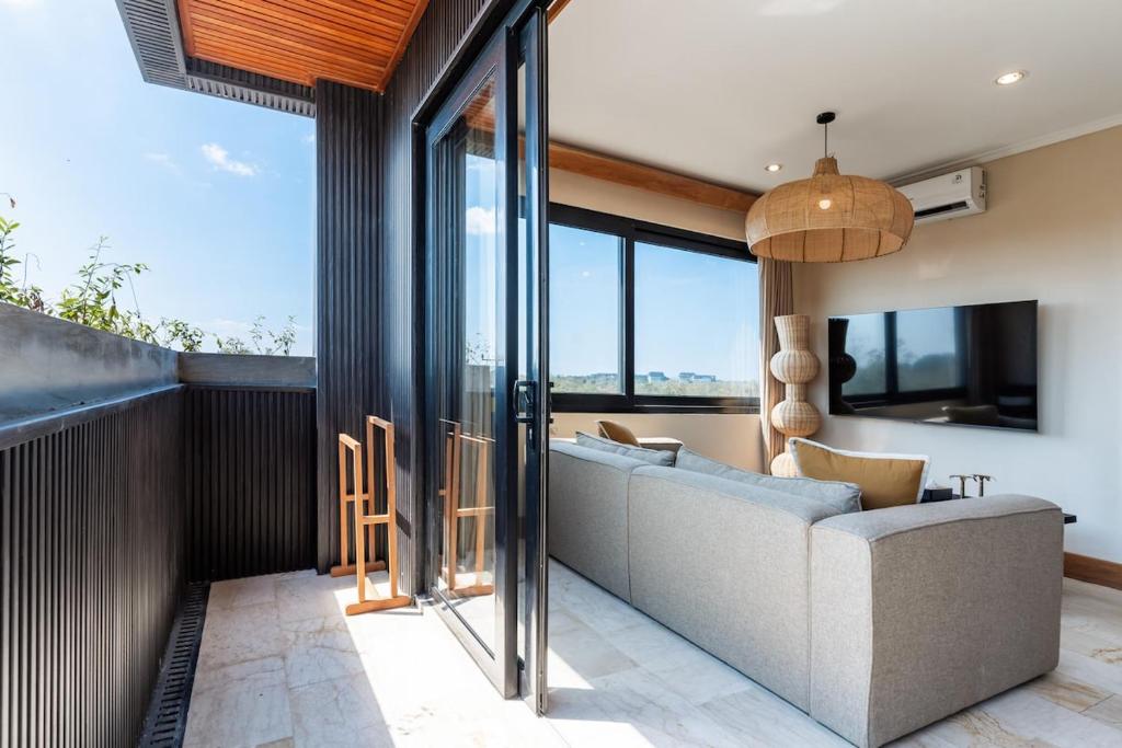 ein Wohnzimmer mit einem Sofa und Glaswänden in der Unterkunft Brand-New Suites with Pool Minutes from Beach in Bingin Beach