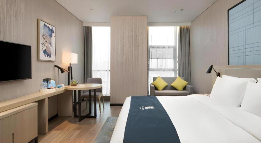 Una habitación de hotel con una cama grande y un escritorio. en Echarm Hotel Changsha Gaoqiao, en Changsha