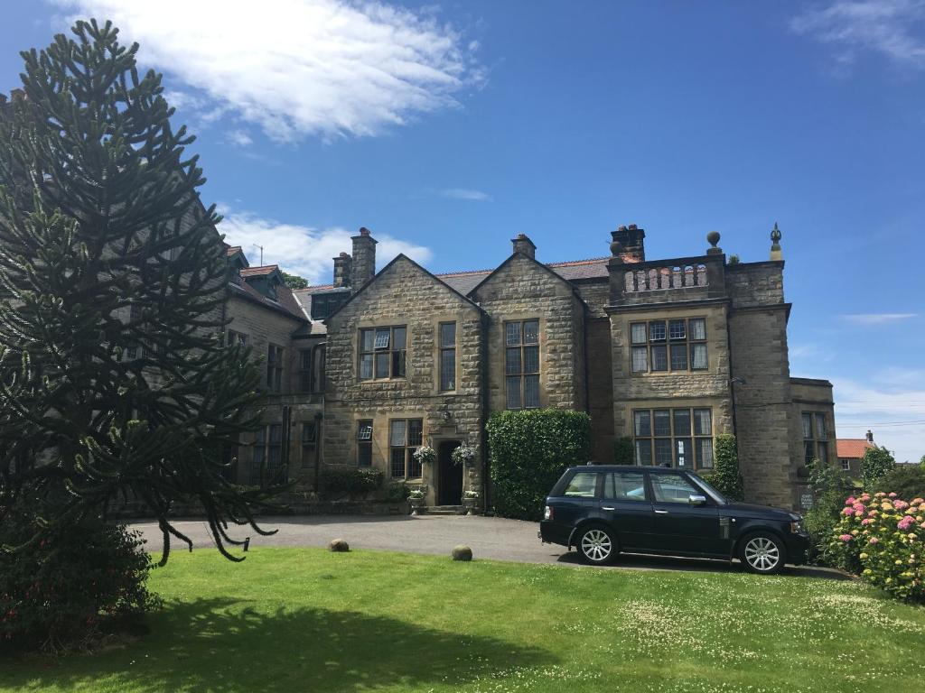 een zwarte auto geparkeerd voor een huis bij Dunsley Hall Country House Hotel in Whitby