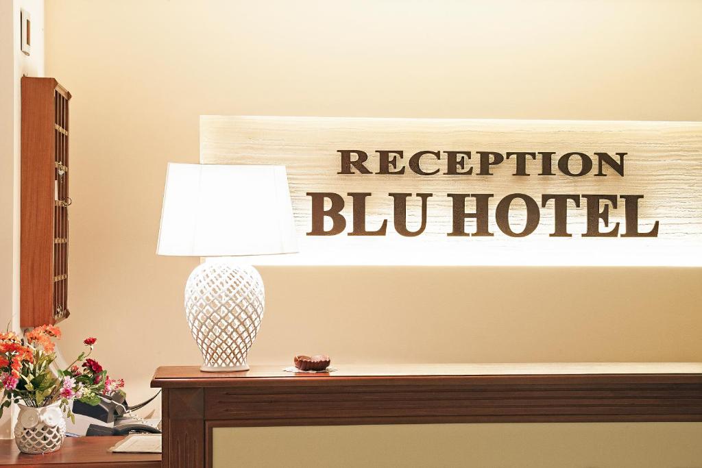 una lámpara en una mesa con un cartel que diga recepción bl hotel en Blu Hotel, en San Nicola Manfredi