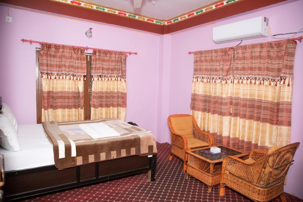 チトワンにあるHotel Sauraha Gaida Houseのベッドとテーブルと椅子のある寝室