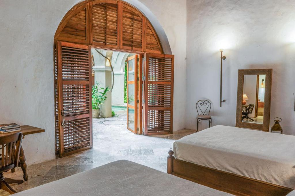 ein Schlafzimmer mit einem Bett, einem Tisch und einem Spiegel in der Unterkunft Casa Trujillo in Cartagena de Indias