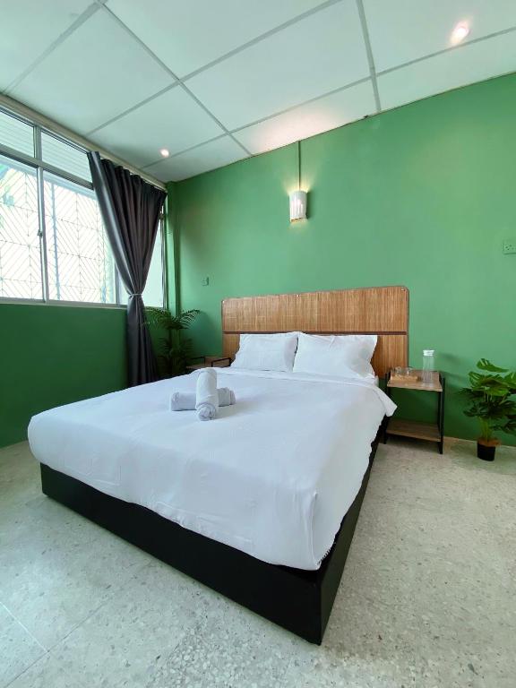 a large bed in a green room with a large white bed sidx sidx at Sembilan Inn by Soft Loft in George Town