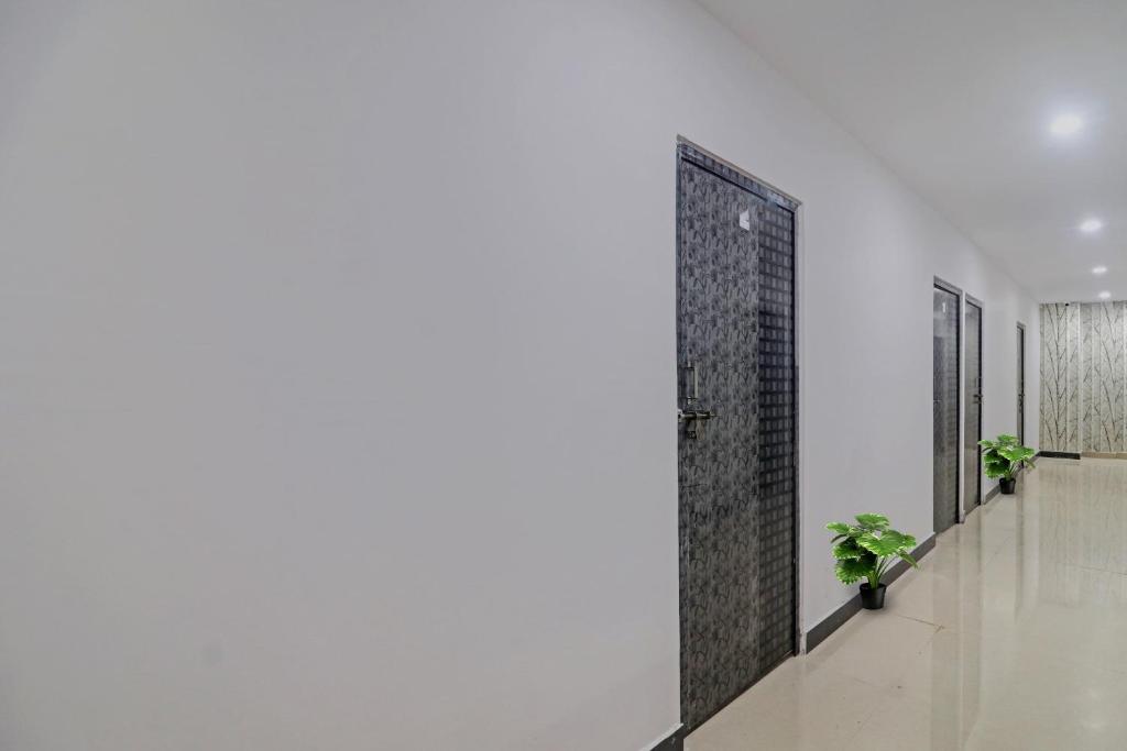 a hallway with two potted plants and a door at Super Hotel O Alwal Residency in Hyderabad