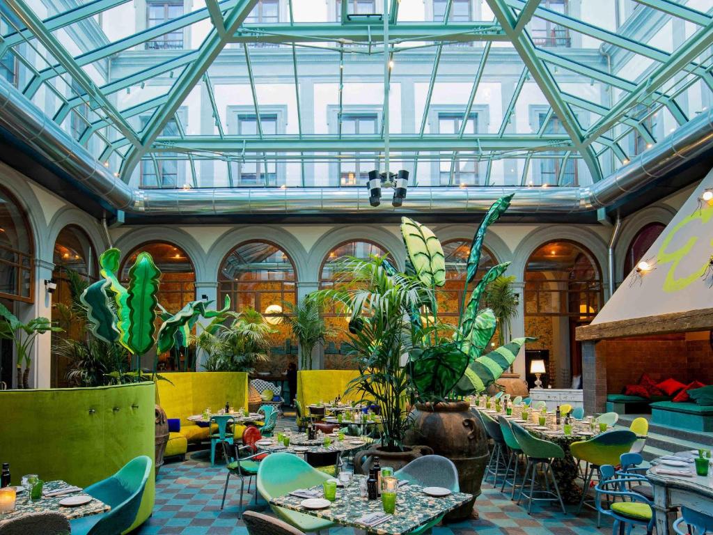 a restaurant with tables and chairs and a glass ceiling at 25hours Hotel Florence Piazza San Paolino in Florence
