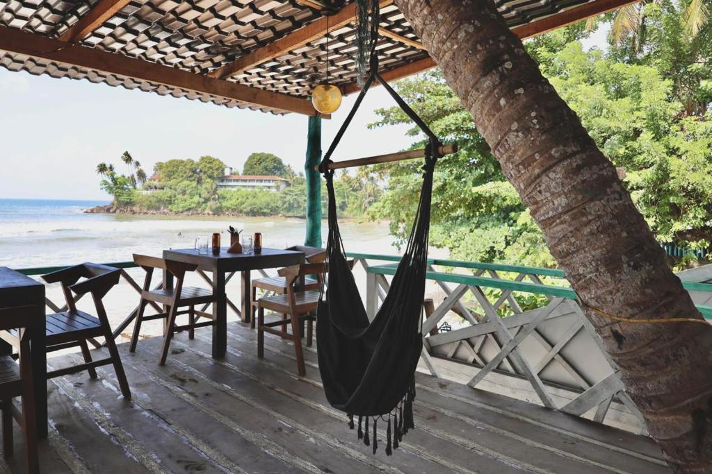 a hammock on a deck with a view of the beach at Ceylon Heart Beach Villa in Galle