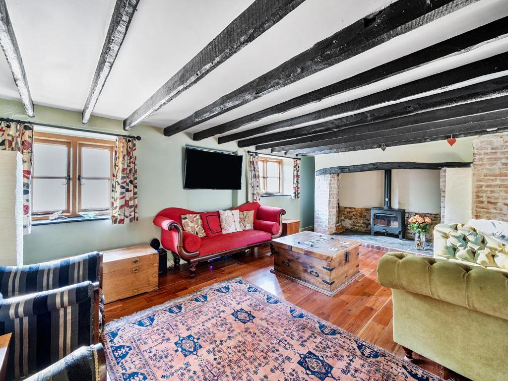 ein Wohnzimmer mit einem roten Sofa und einem Kamin in der Unterkunft Cider Cottage in Fordingbridge
