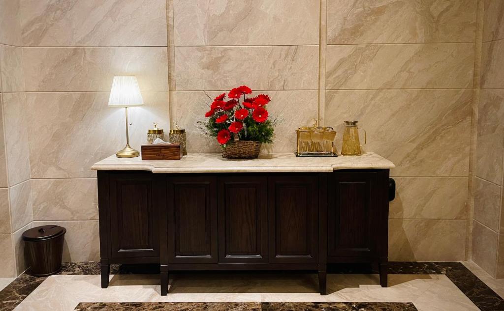 Maccal Boutique Hotel Dalat في دالات: طاولة مع إناء من الزهور ومصباح