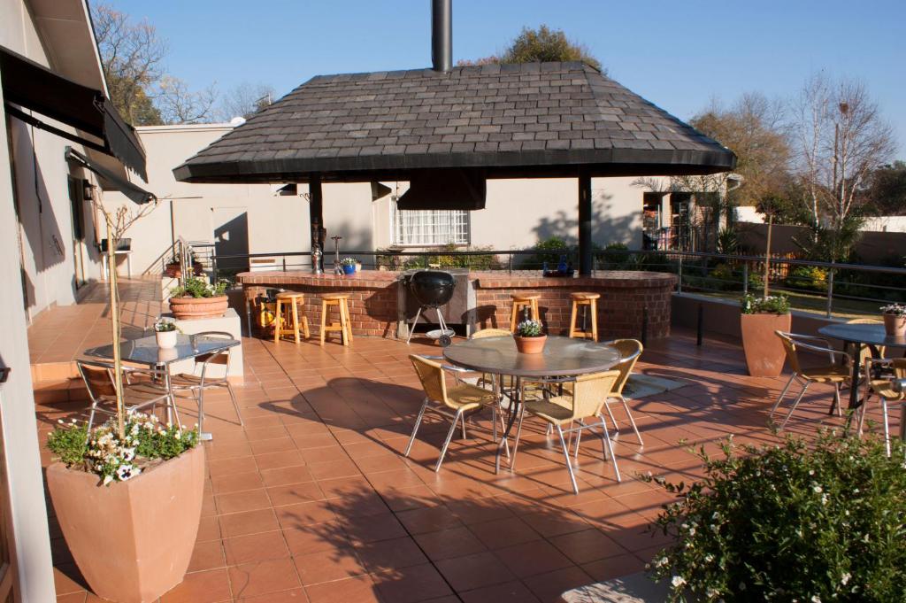 a patio with tables and chairs and an umbrella at 125 on Van Buuren Road Guest House in Johannesburg