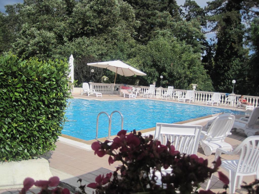 - une piscine avec des chaises blanches et un parasol dans l'établissement Hotel Gioia Garden, à Fiuggi