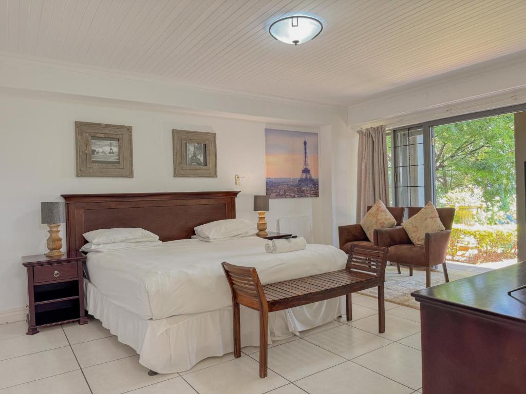 a bedroom with a bed and a desk and a chair at Amoris Guesthouse on Orion in Pretoria