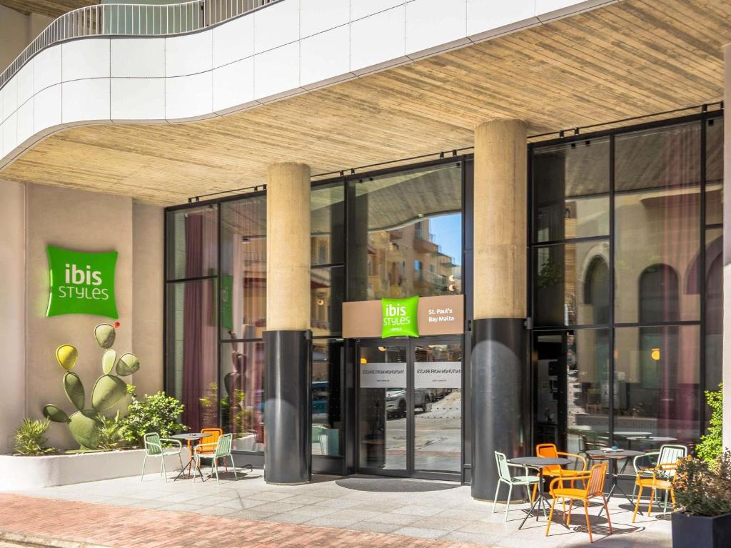 Un edificio con sillas y mesas delante. en ibis Styles ST Pauls Bay Malta, en St Paul's Bay