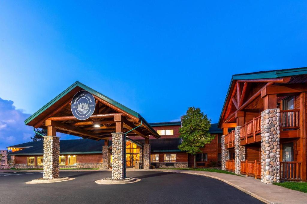 a log cabin with a sign in front of it at Shell Lake Lodge, a Travelodge by Wyndham in Shell Lake