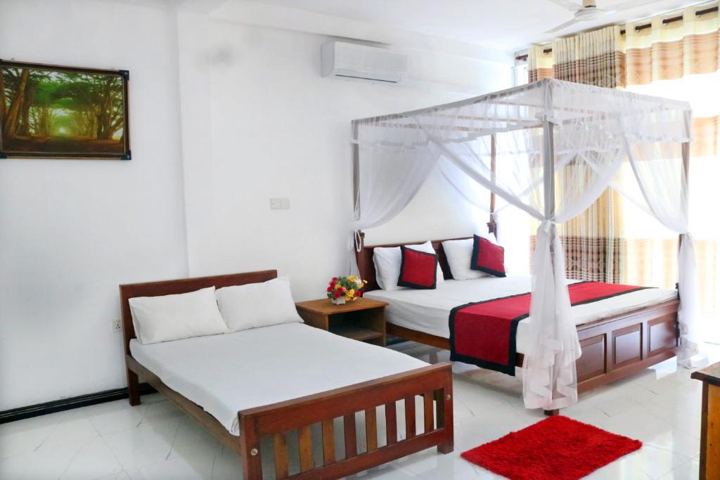 a bedroom with two beds and a canopy bed at Unaway Holiday Home in Unawatuna