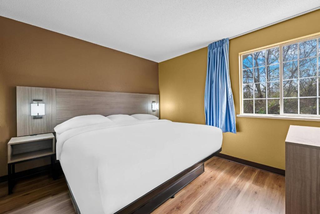 un grand lit blanc dans une chambre avec une fenêtre dans l'établissement Suburban Studios Charlotte - Executive Park, à Charlotte
