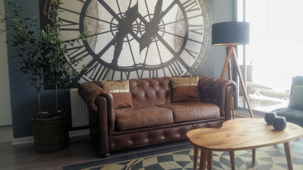 a brown couch in a living room with a large clock at Apartamento Boutique Viña del Mar in Viña del Mar