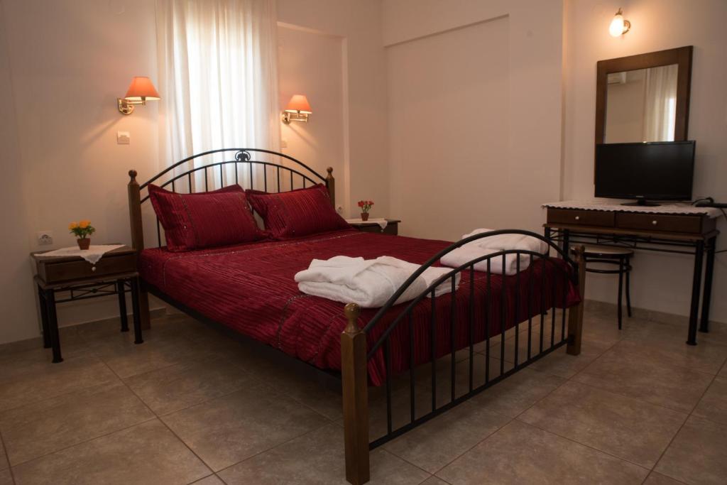 a bedroom with a bed with red sheets and a desk at Vrokastro Apartments in Istro