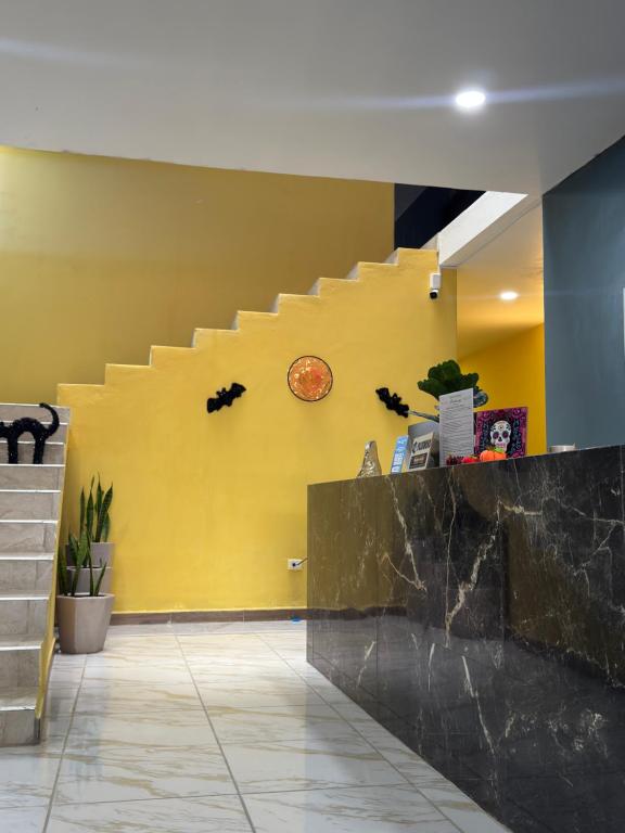 a yellow wall with a staircase and a clock at Hotel Mochomos Huajuapan in Huajuapan de León