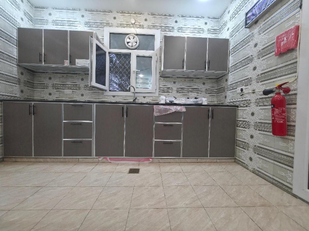 a kitchen with grey cabinets and a window in a room at Sand Adventures Oasis in Bidiyah